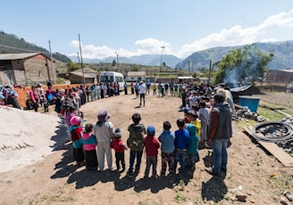 people standing forming circle near house under blue sky during daytime