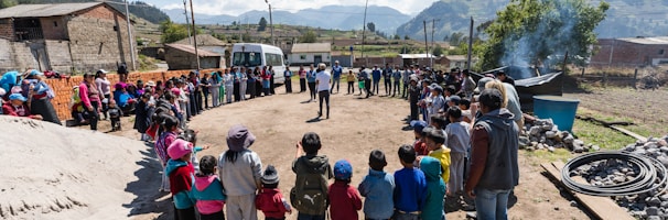 people standing forming circle near house under blue sky during daytime