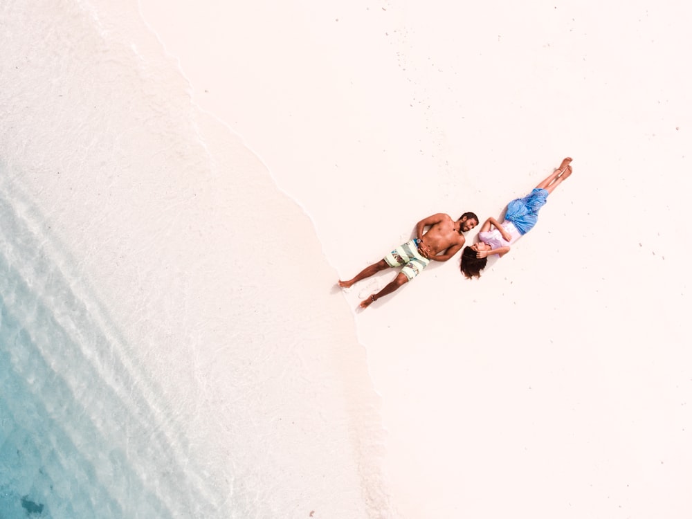 bird's eye view of man and woman lying on shore