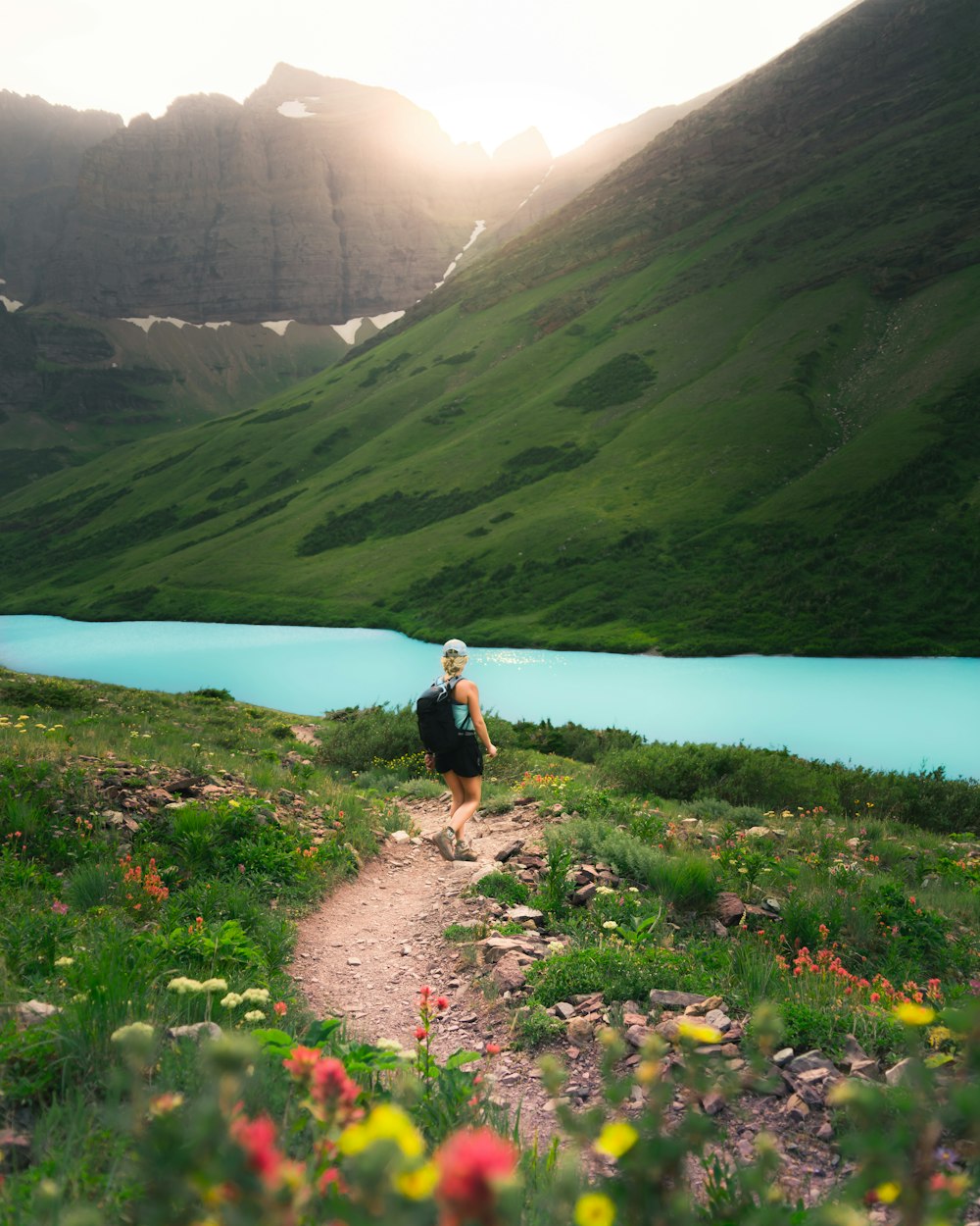 person with backpack walking near calm water