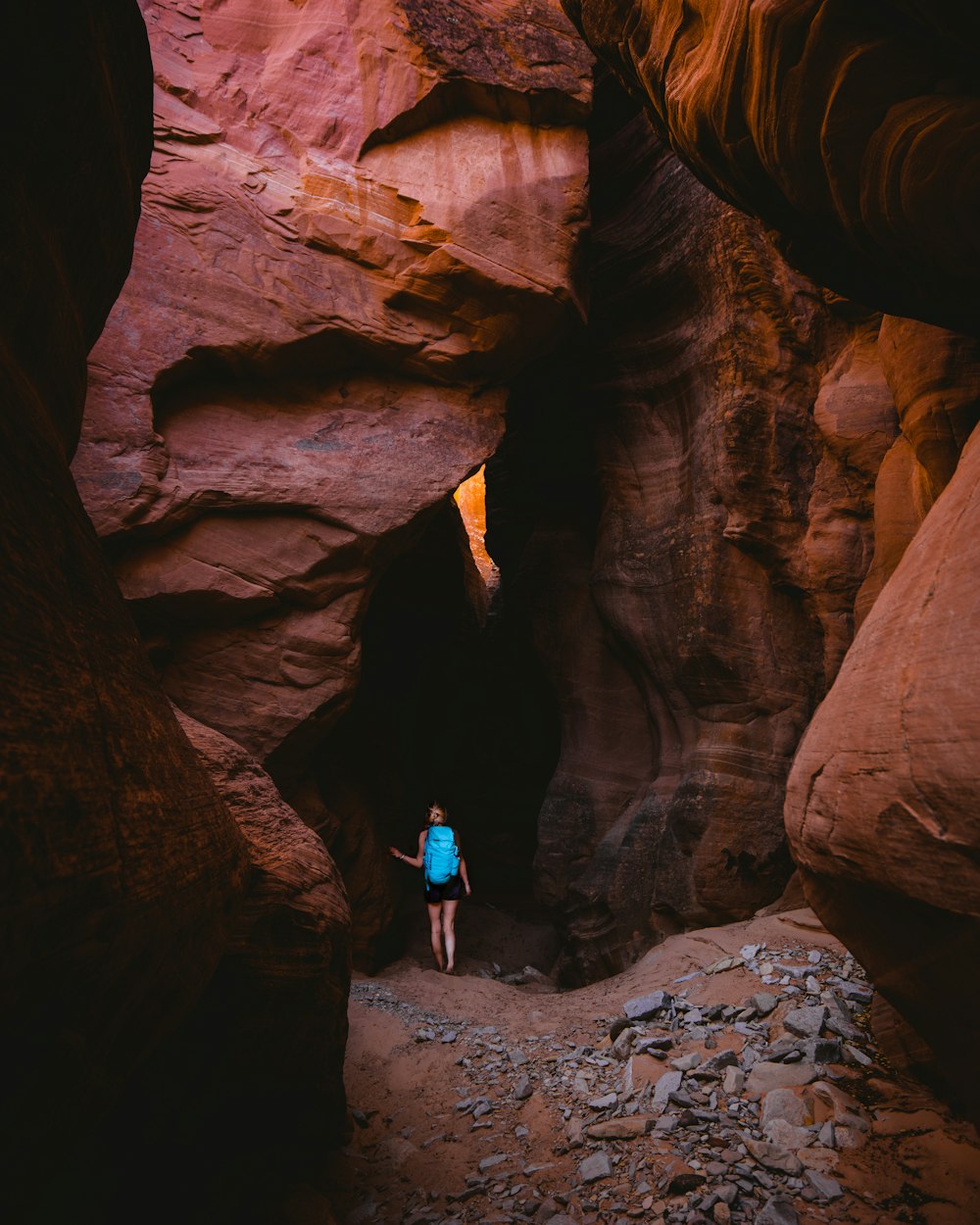 woman walking between brown rock formation during daytime