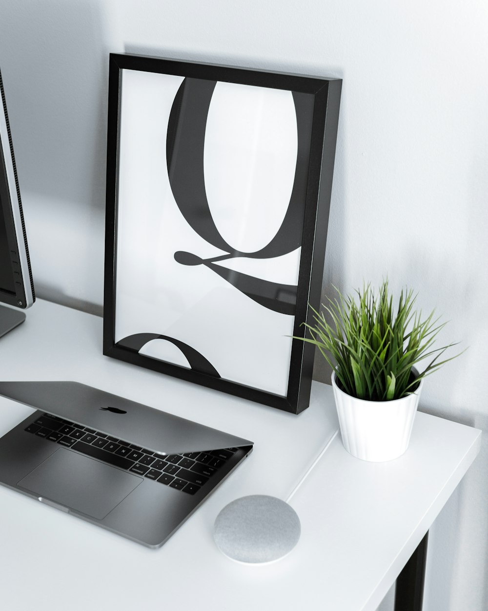 MacBook Air and charcoal Google Home mini on white table