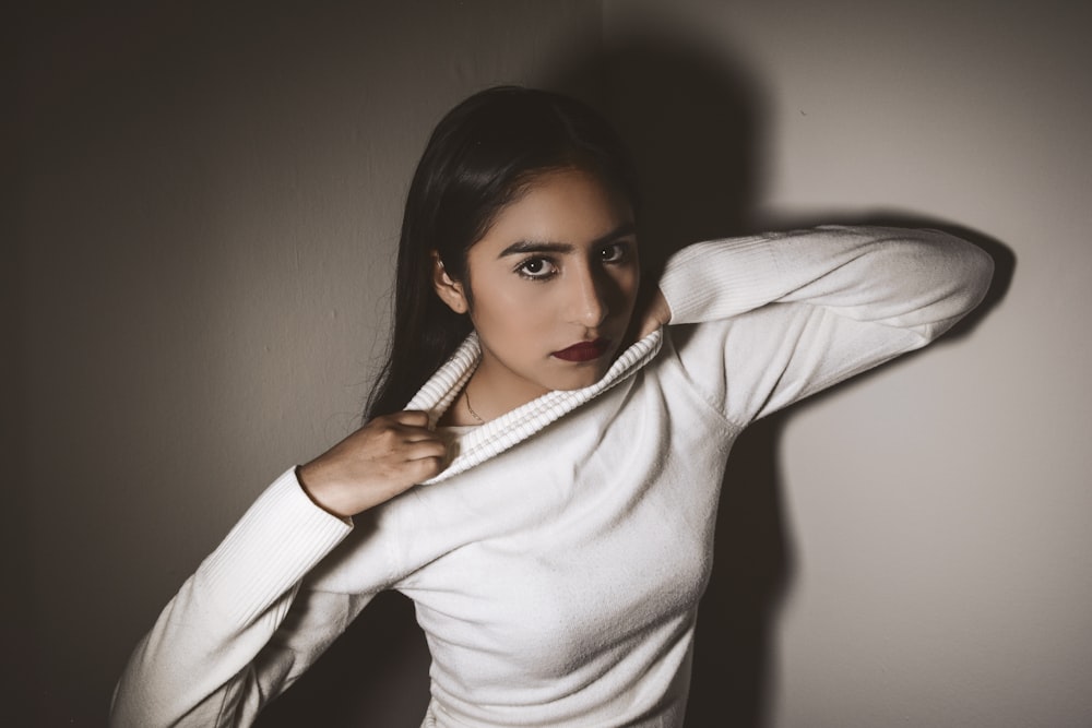 woman in white sweater grabbing out own shrit