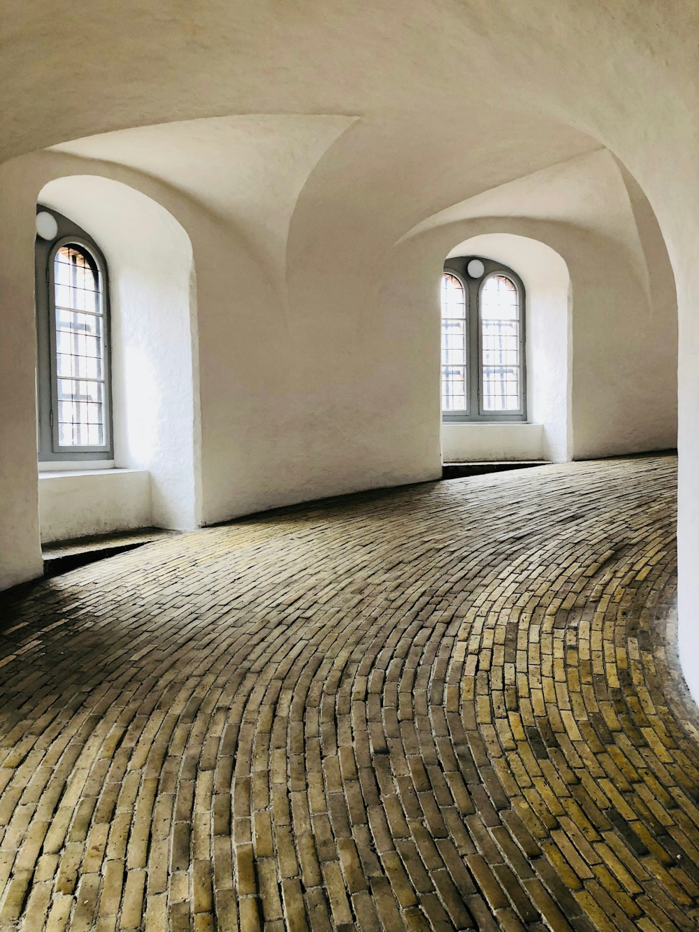 white painted swerving hall with brick floor