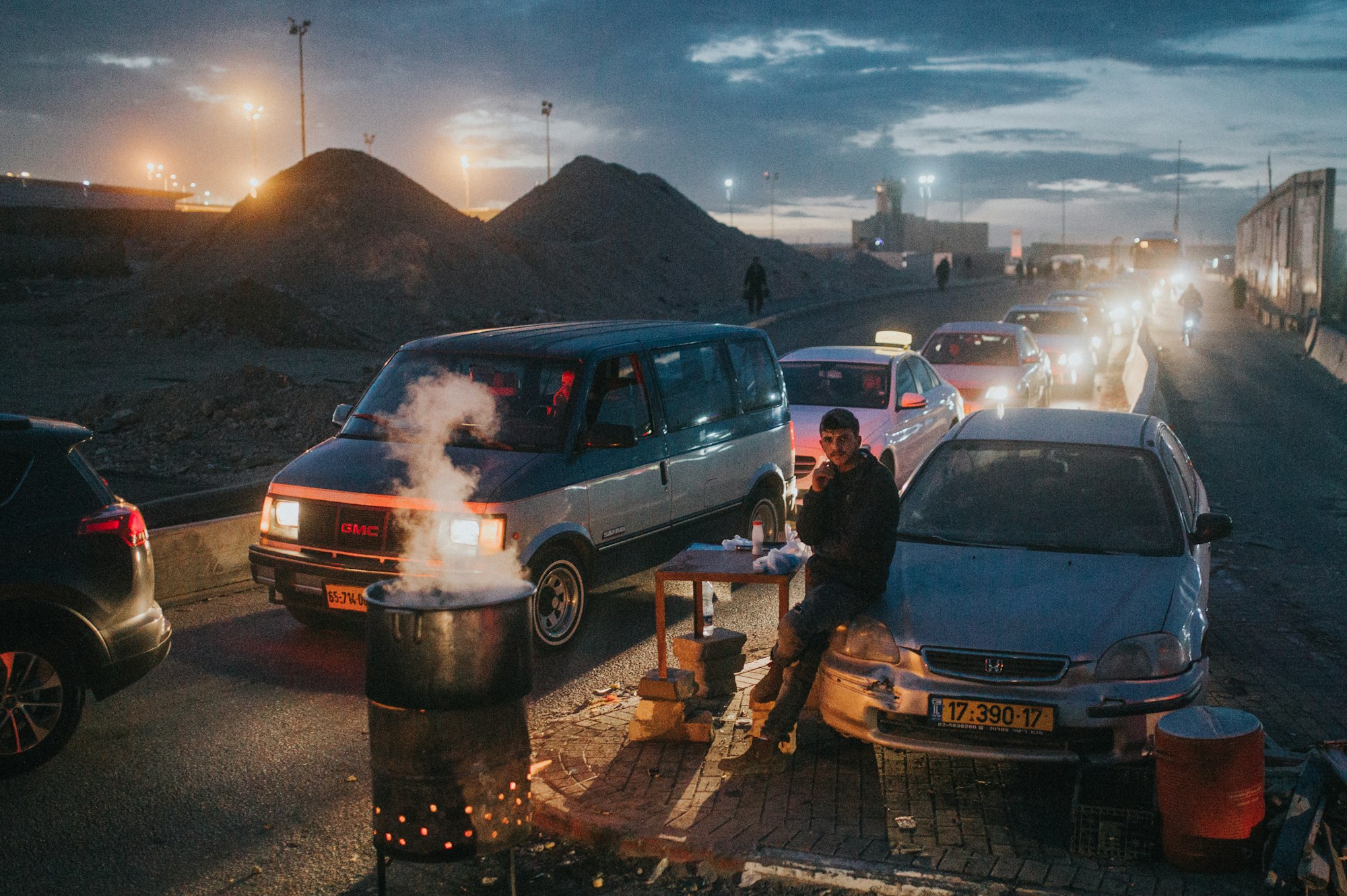 A man waiting by lines of cars going through a checkpoint from Ramallah, Palestine to enter Israel.