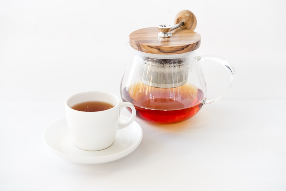 tea on glass teapot beside teacup with saucer
