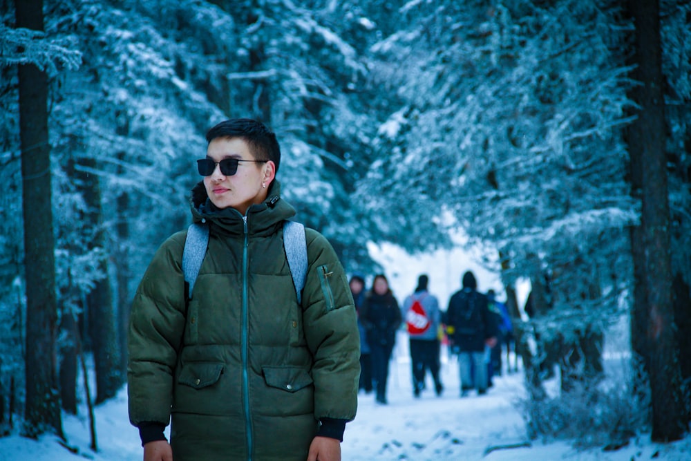 man wearing green jacket standing in the middle of foreset