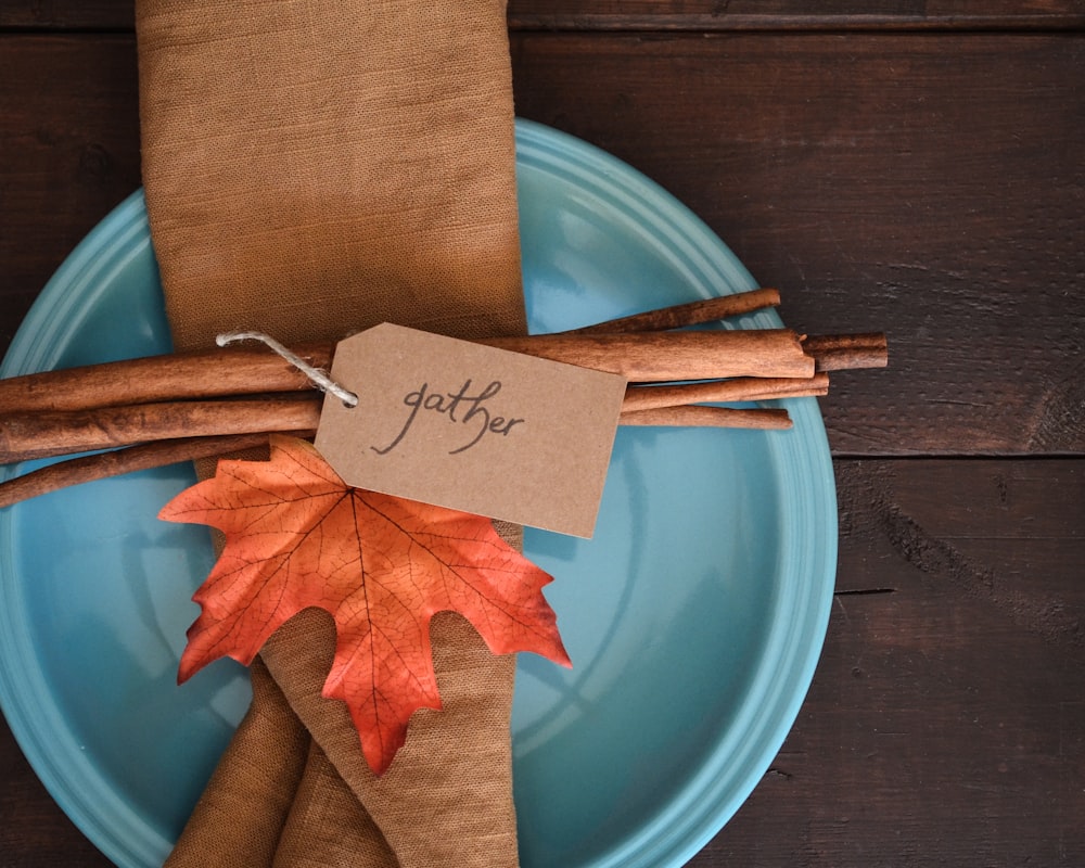 a blue plate topped with an orange and brown leaf