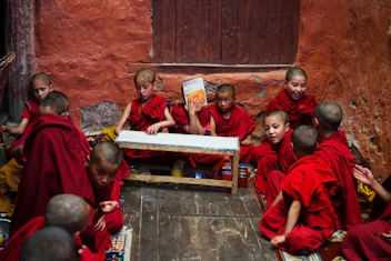 boys in red robe sitting on the floor