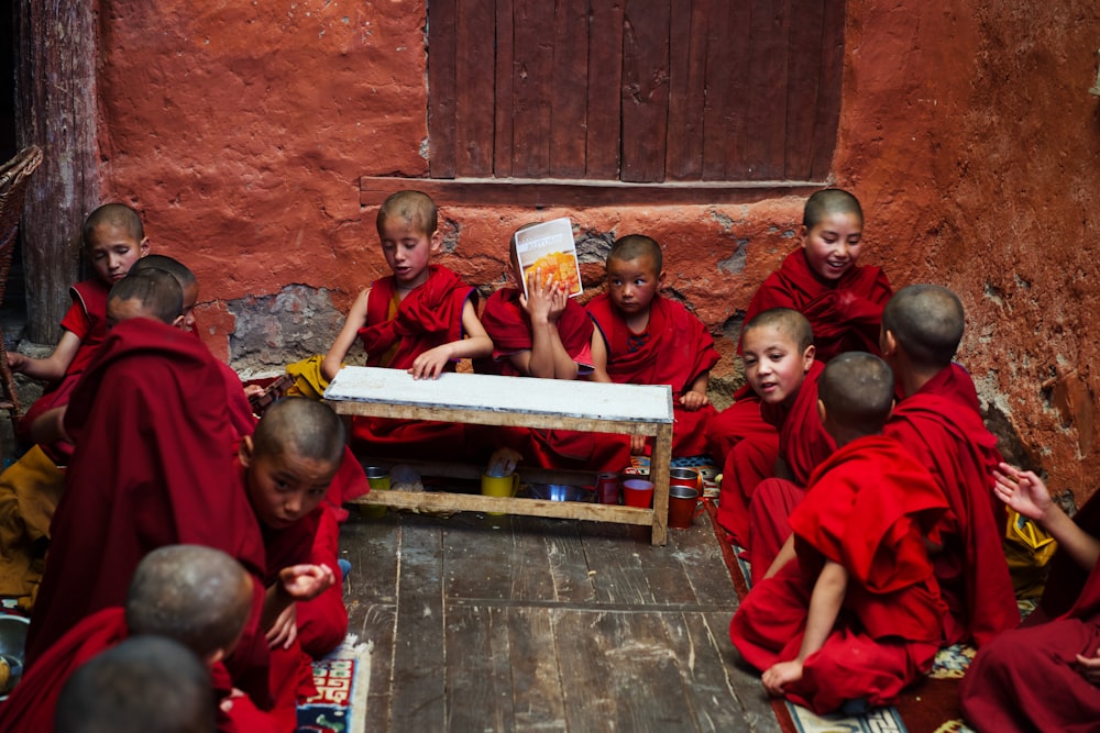 boys in red robe sitting on the floor