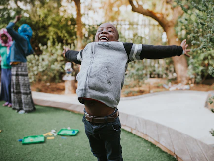 A joyful child stretching outdoors in soft morning light, embodying health and vitality.