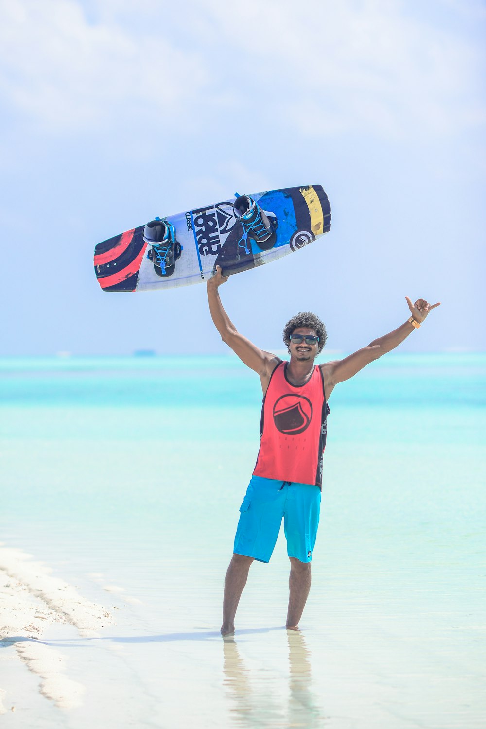 man wearing red and black tank top holding wakeboard