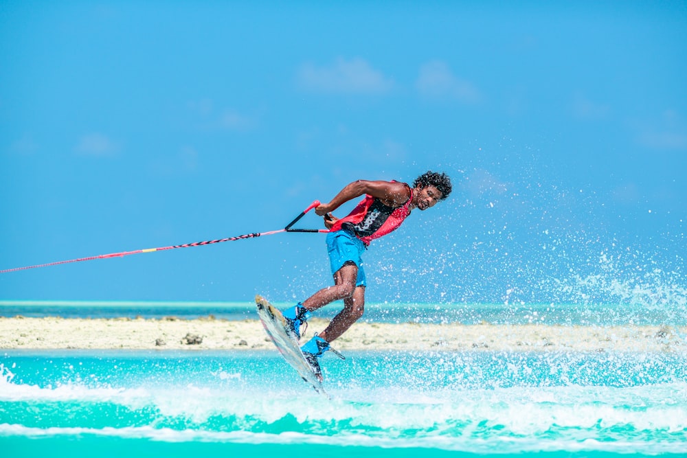 homme en débardeur rouge faisant des sports nautiques pendant la journée