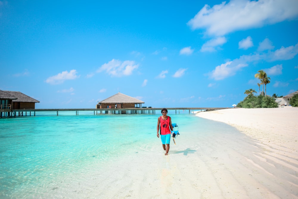 man walking on seashore under blue sky