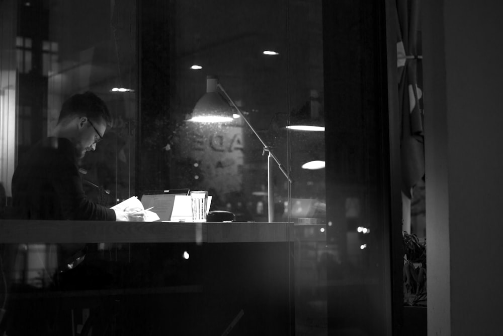 um homem sentado em uma mesa em frente a uma janela
