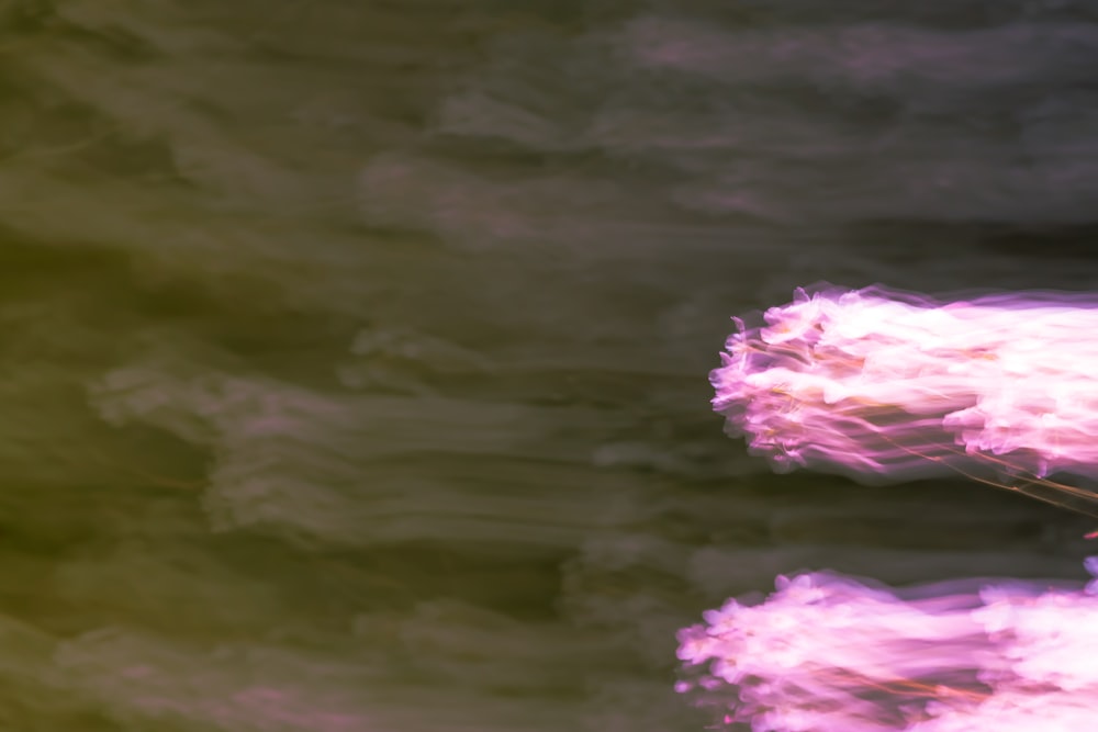 a plane flying through a cloudy sky with pink clouds