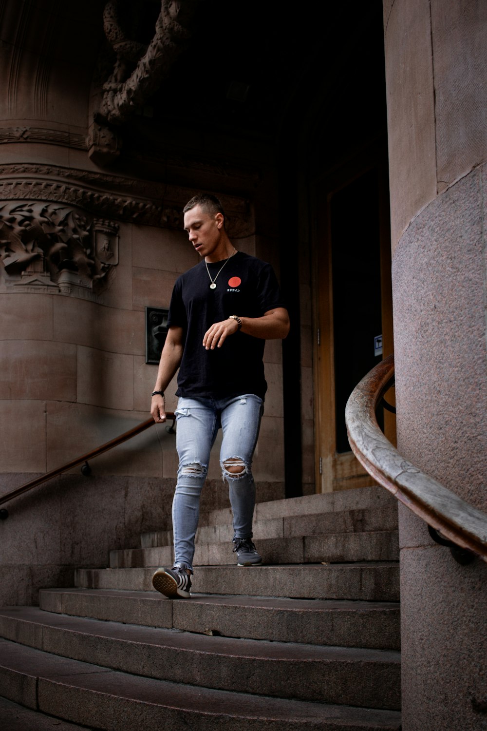 man in black T-shirt and distressed jeans walking down stairs