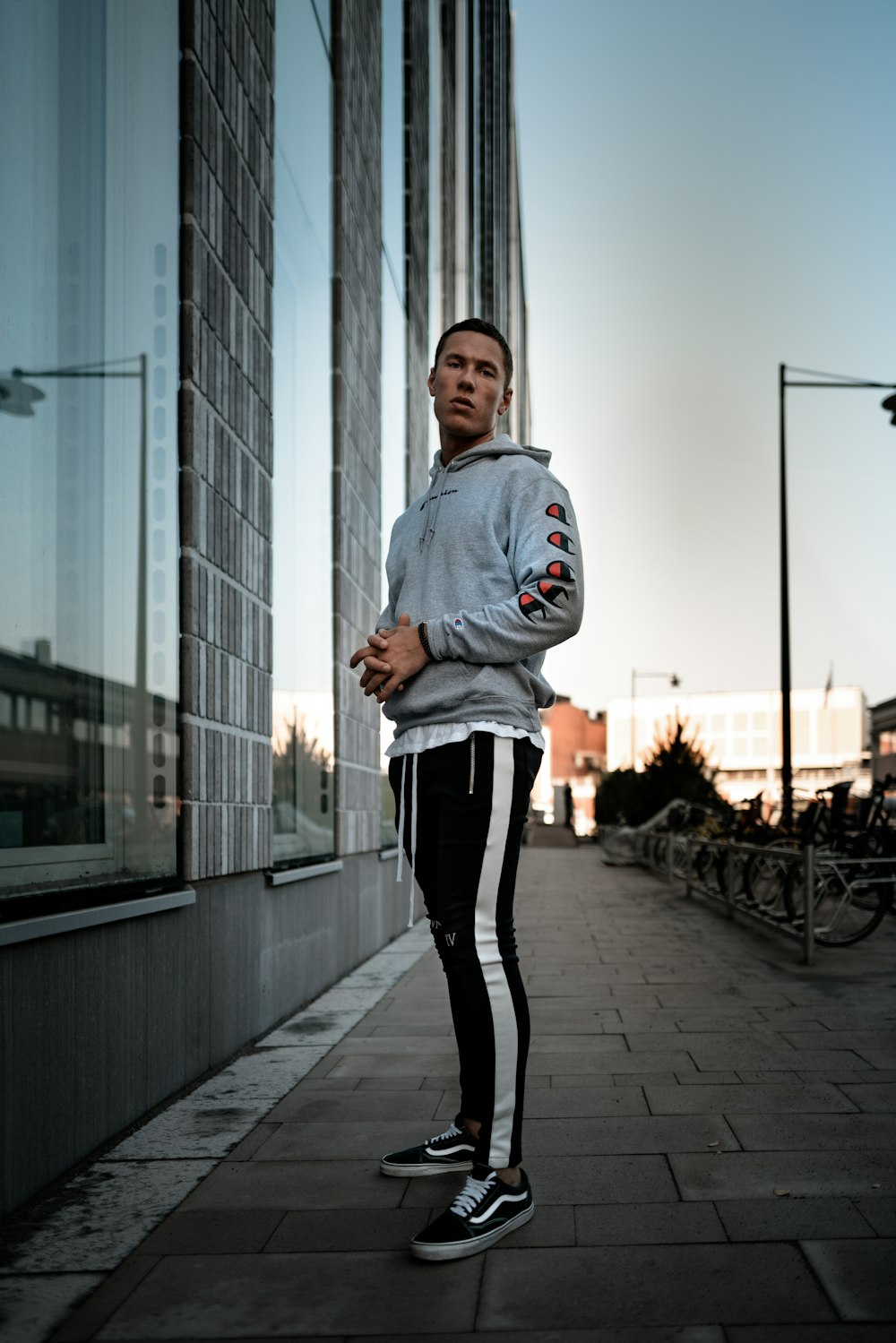 man in a gray sweater and black and white track pants