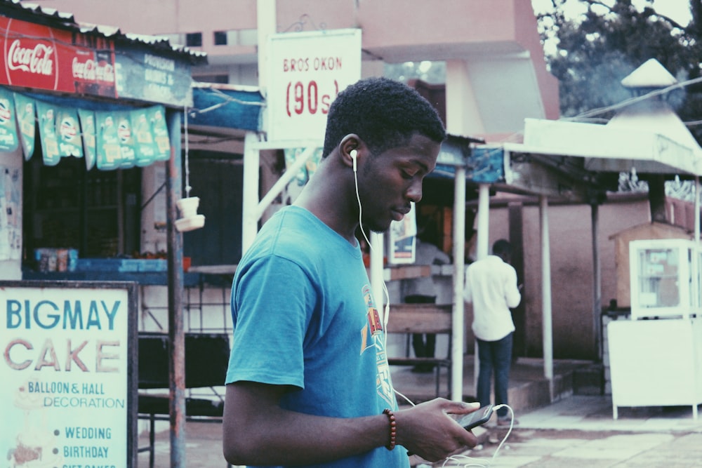 man listening to earphones near store