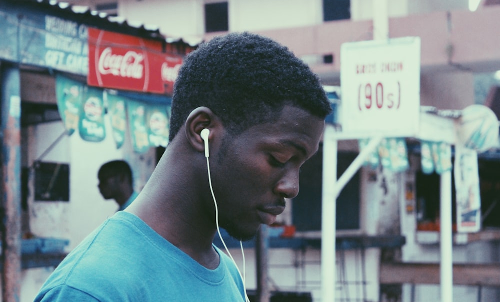 man wearing blue crew-neck shirt wearing earbuds