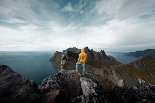 man standing on mountain peak in Senja Norway