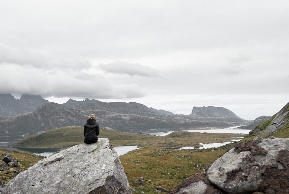 woman sitting on gray rock formation during daytime