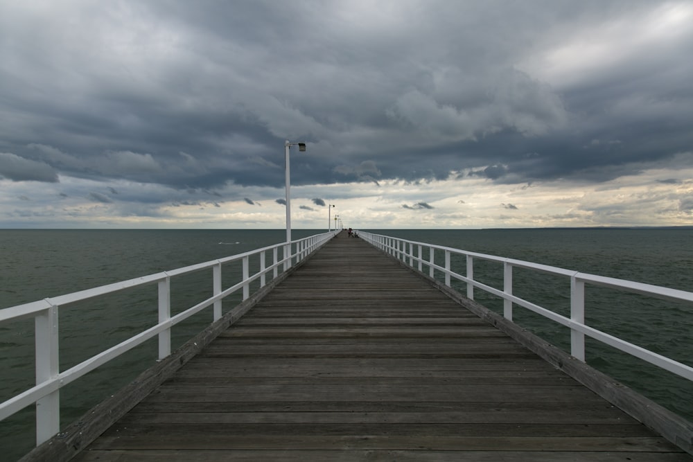 a long pier extending into the ocean under a cloudy sky