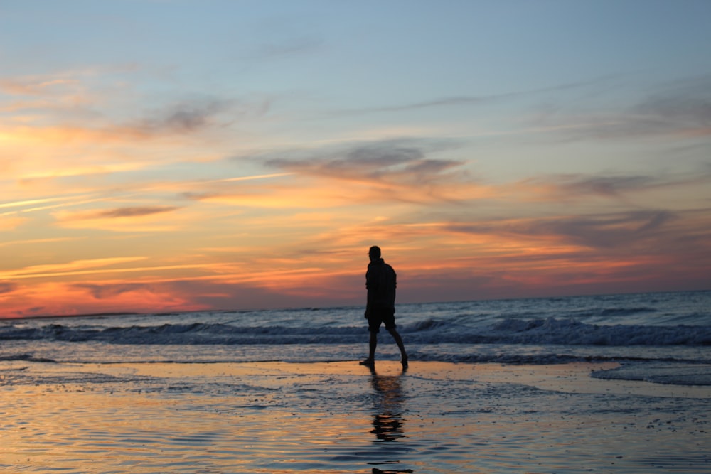 silhouette of man walking on seashore