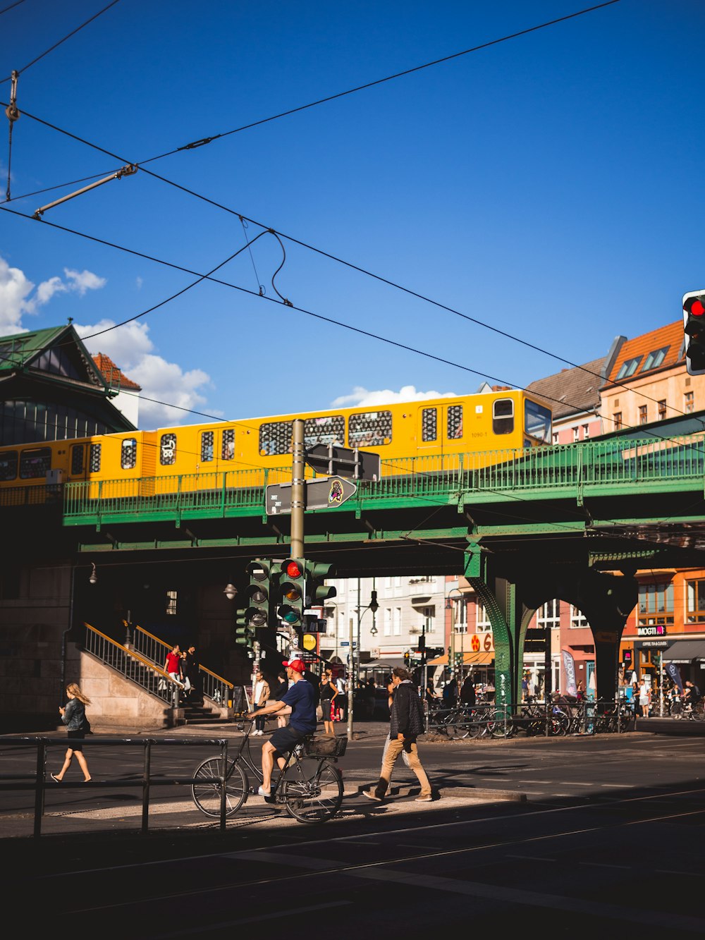 people walking and riding bike at the streets near bridge train