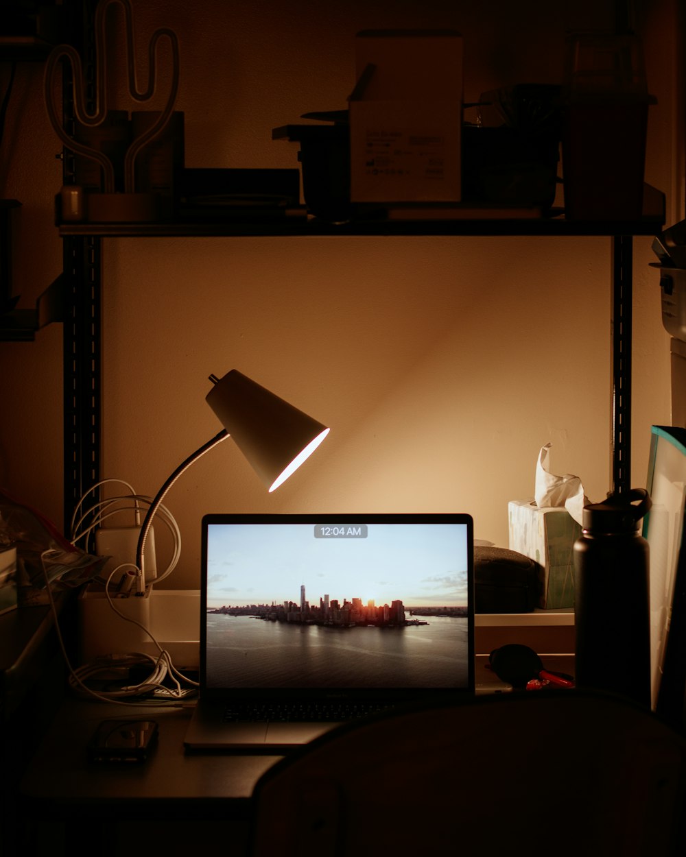 Portátil encendido al lado de la lámpara de escritorio encendida