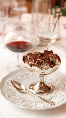 Signature tiramisu served in a glass with gold accents on a black marble table.