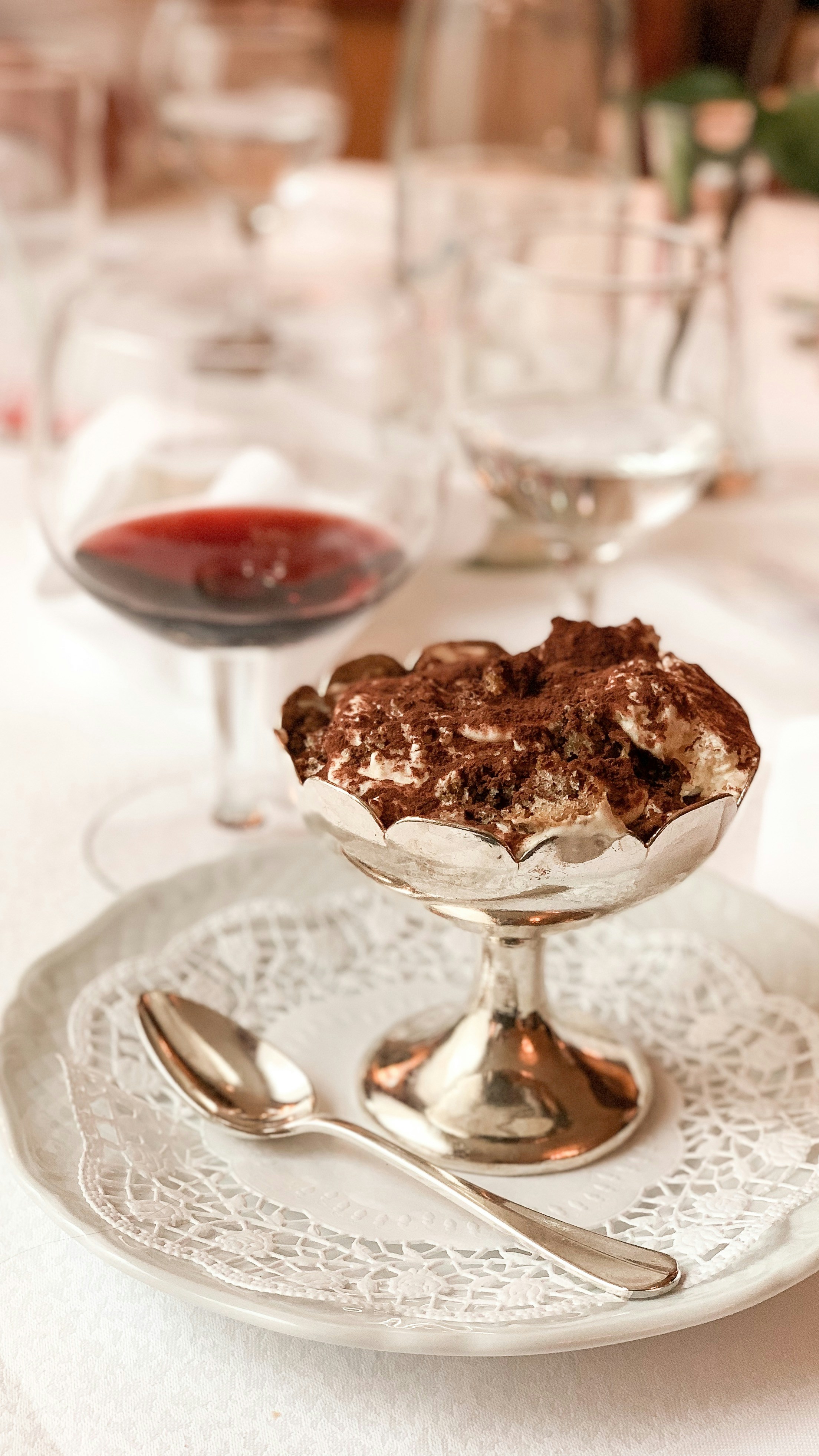 A cup of tiramisu with a glass of red wine at a restaurant