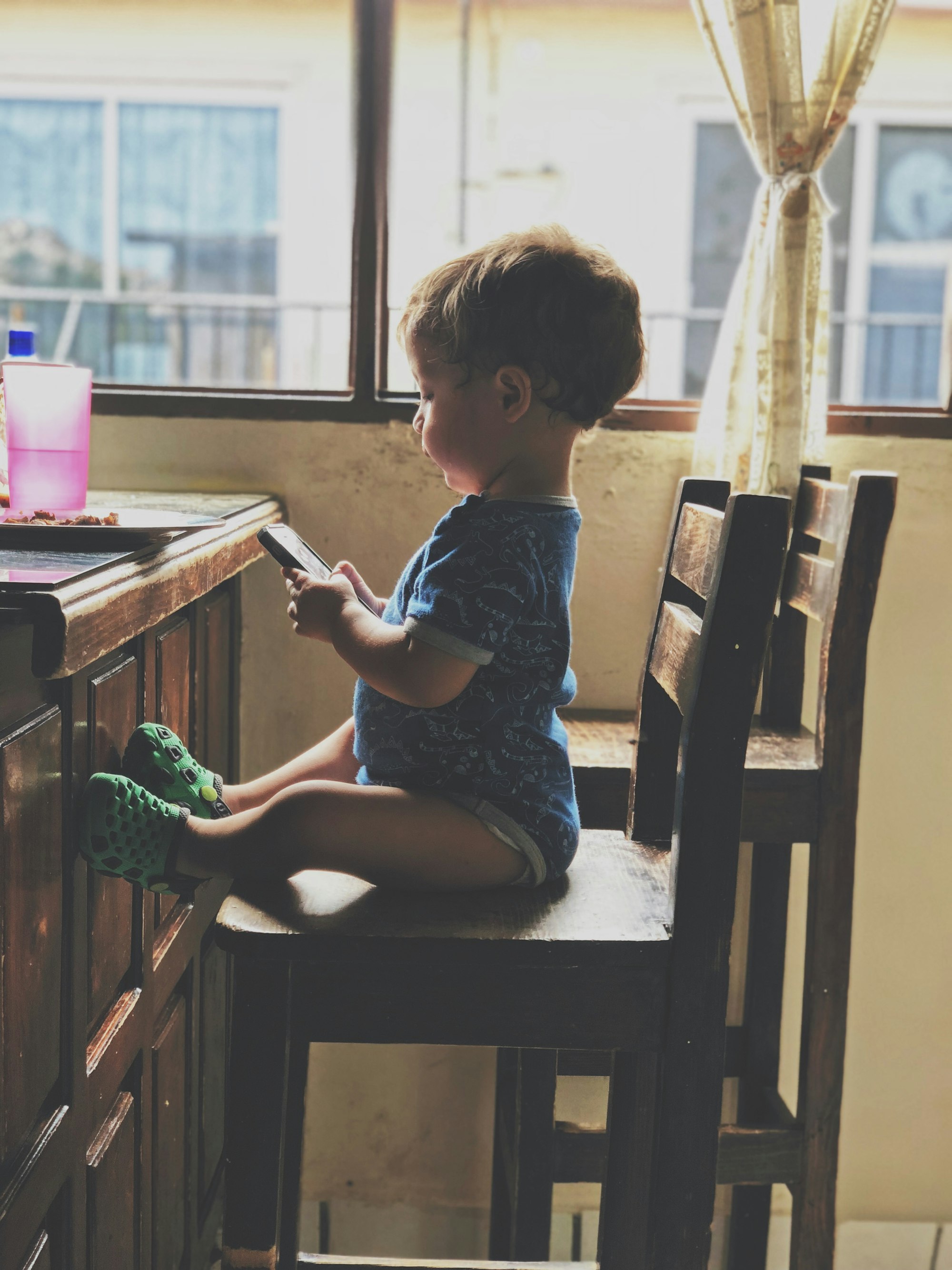 boy holding smartphone while sitting on the chair