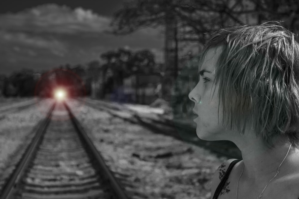 grayscale photography of woman near train track
