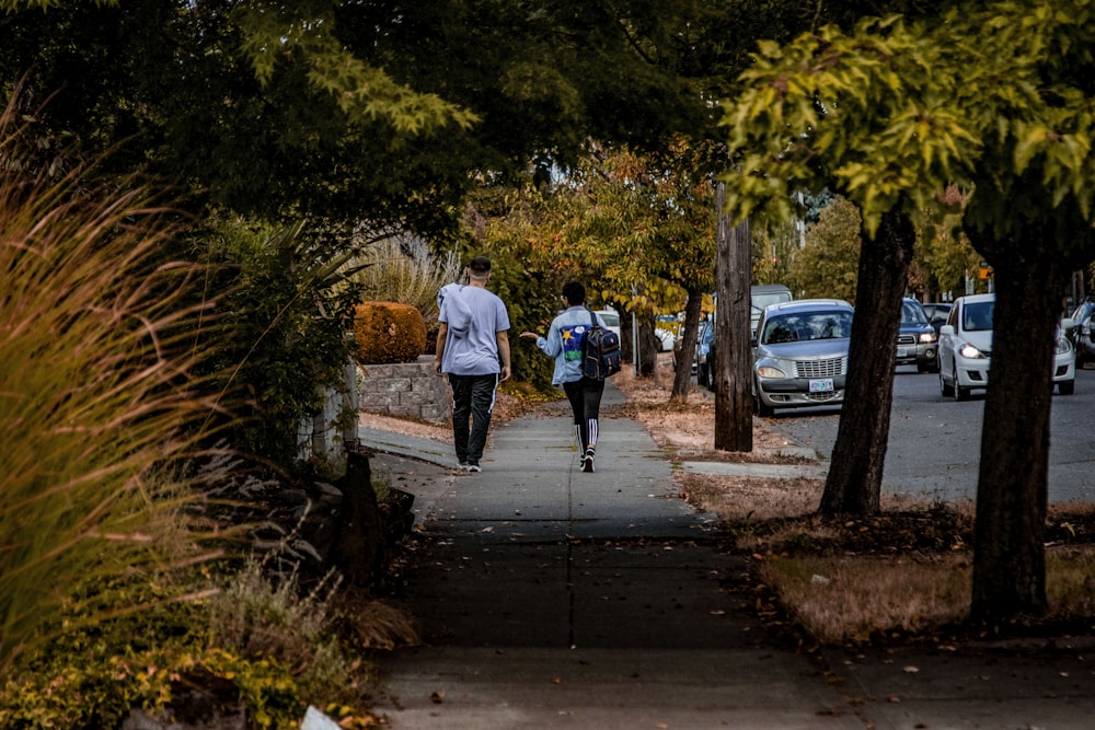 man and woman walking on sidewalk near road and cars