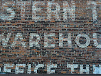 Close-up of aged factory bricks with faded painted signage from the early 1900s.