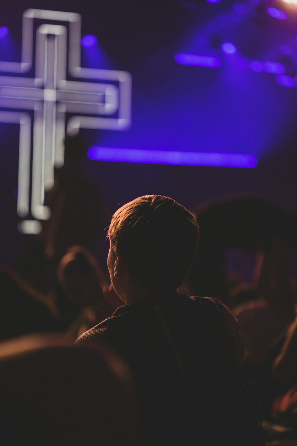 uma pessoa em pé diante de uma cruz em um palco