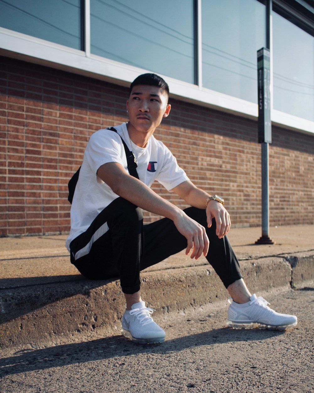 man sitting on curb during day