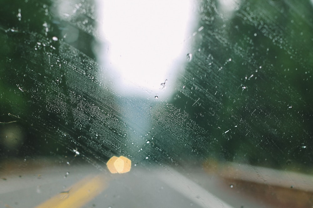 Ein Blick auf eine Straße durch eine regenbedeckte Windschutzscheibe