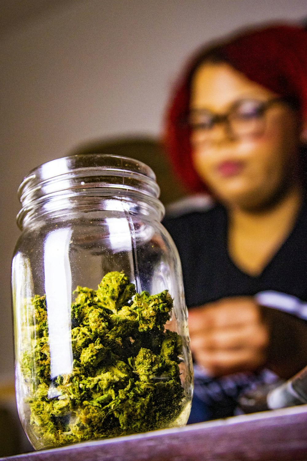 selective focus photography of kush on jar near woman