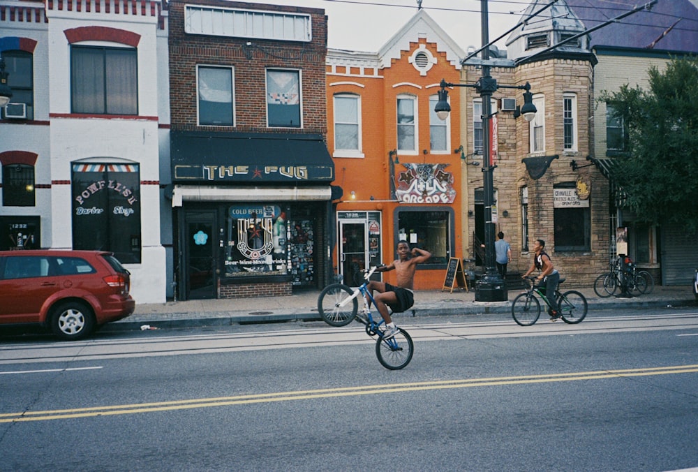 topless man riding bicycle near establishments