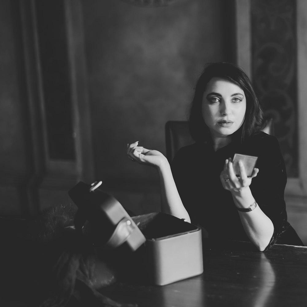 woman holding cosmetic sitting beside table