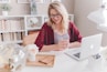 A smiling working mom sitting at her desk with a planner and a cup of tea, surrounded by soft blue and teal accents.