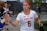 A female athlete in a white jersey with the word 'Maryland' and the number 6, giving high-fives to people on the sidelines. She wears a red headband and appears focused as she walks. Other team members and onlookers are visible in the background.