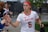A female athlete in a white jersey with the word 'Maryland' and the number 6, giving high-fives to people on the sidelines. She wears a red headband and appears focused as she walks. Other team members and onlookers are visible in the background.