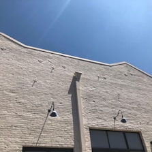 Workers building a sturdy brick wall under a bright blue sky.