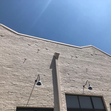 A newly constructed residential building with clean brick walls and smooth plaster finish under a clear blue sky.