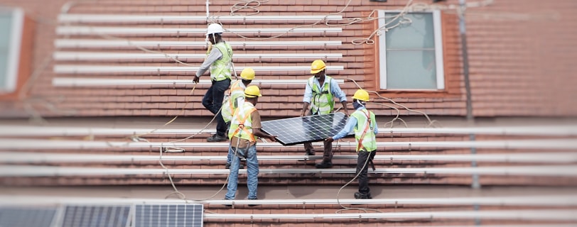 men holding solar panel on roof