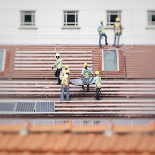 men holding solar panel on roof