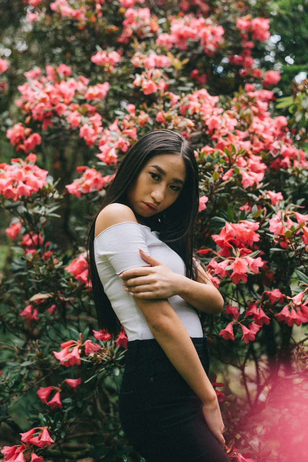 woman looking over her right shoulder standing beside flowers